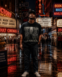 Man in black "LIVE AT THE PEEP SHOW N.Y.C." cotton t-shirt and jeans on a wet Times Square street at night.