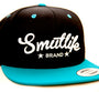 Black and teale Smutlife Tri-Star snapback hat with white embroidered logo and flat brim.