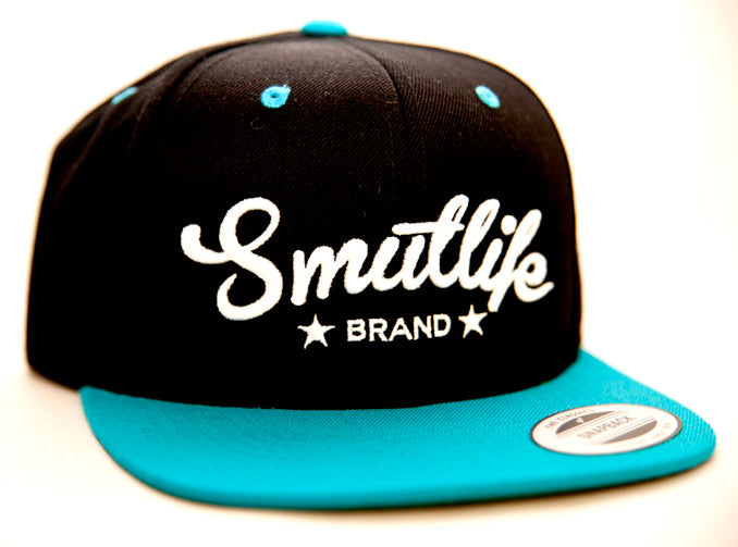 Black and teale Smutlife Tri-Star snapback hat with white embroidered logo and flat brim.