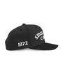 Black SMUTLIFE CREW 1972 snapback hat with white embroidered text on front and "1972" on left panel.
