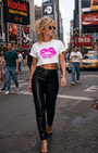 Women's white cropped TONGUE TWISTER tee with fuchsia lips graphic, paired with black leather pants.