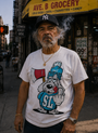 White men's Smut Slushie T-shirt with Chilly the dog mascot flipping the bird, worn by a man smoking a cigar.
