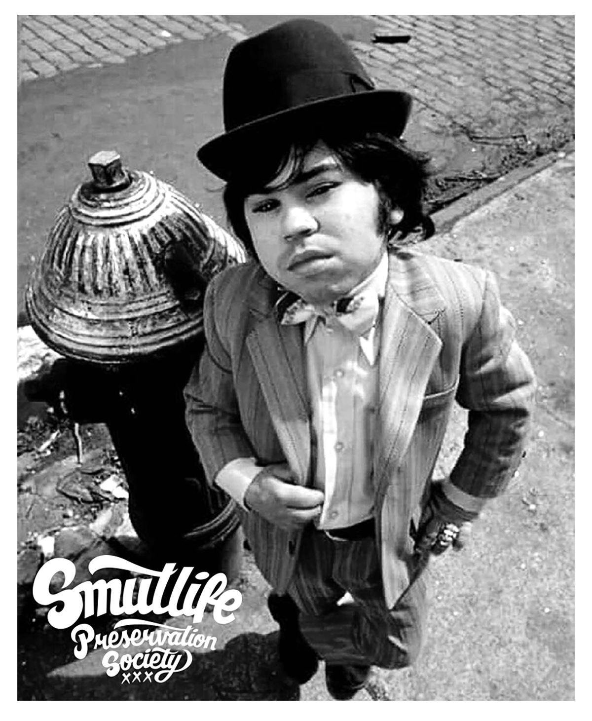 Black and white image of Hervé Villechaize (Tattoo) in a pinstripe suit and bowler hat, standing by a hydrant.