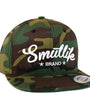 Camo Tri-Star Smutlife Brand snapback baseball hat with white script logo and flat brim.